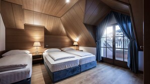 Un dormitorio con dos camas, techo de madera y un amplio ventanal con cortinas.