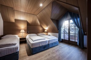 A bedroom with two beds, wooden ceiling, and a large window with curtains.