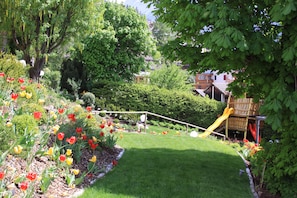 A garden with a slide, a lawn, and a variety of flowers.