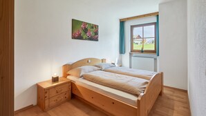 Een slaapkamer met een houten bed, een nachtkastje, een raam met uitzicht en een schilderij aan de muur.