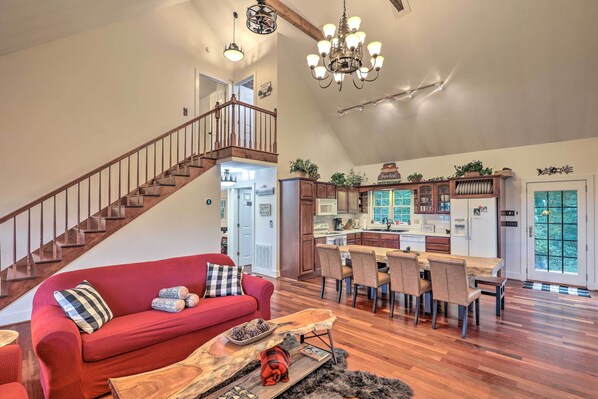 Un salon spacieux avec un canapé rouge, une table basse en bois et un escalier menant à un niveau supérieur.