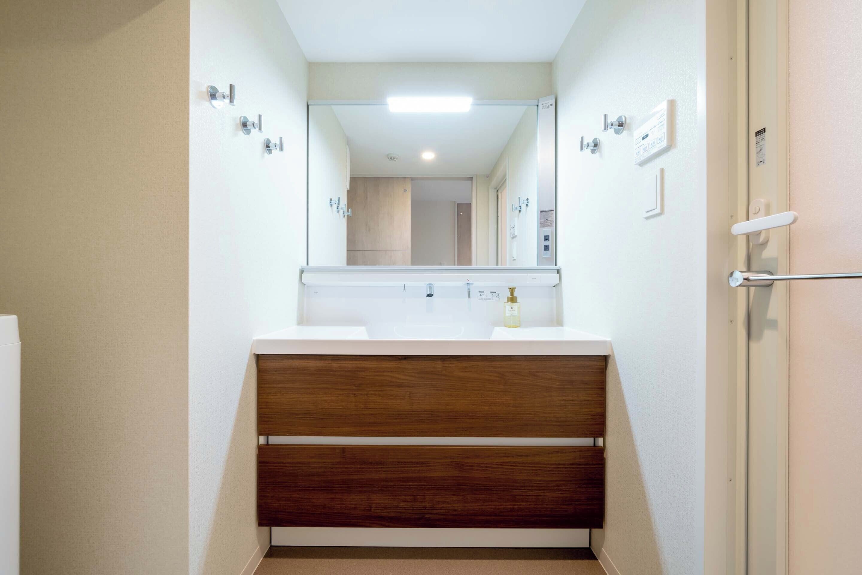 A bathroom with a wooden vanity, a mirror, a sink, and a toilet.