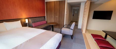Una habitación de hotel con una cama grande, un escritorio, una silla, un televisor y un armario.