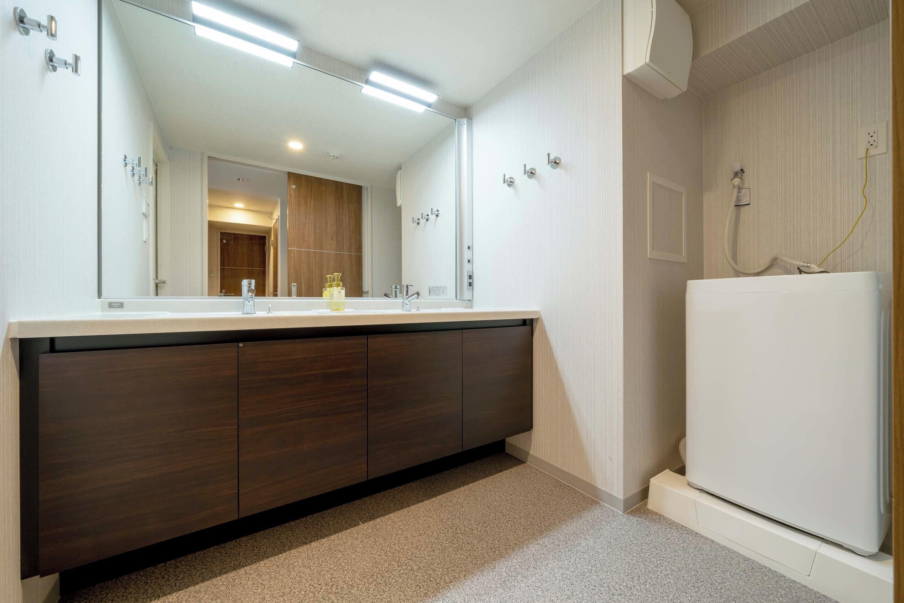 A bathroom with a large mirror, a dark wooden vanity, a white sink, and a white toilet.