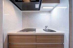 Uma cozinha moderna com fogão embutido, pia e bancada com um tablet.
