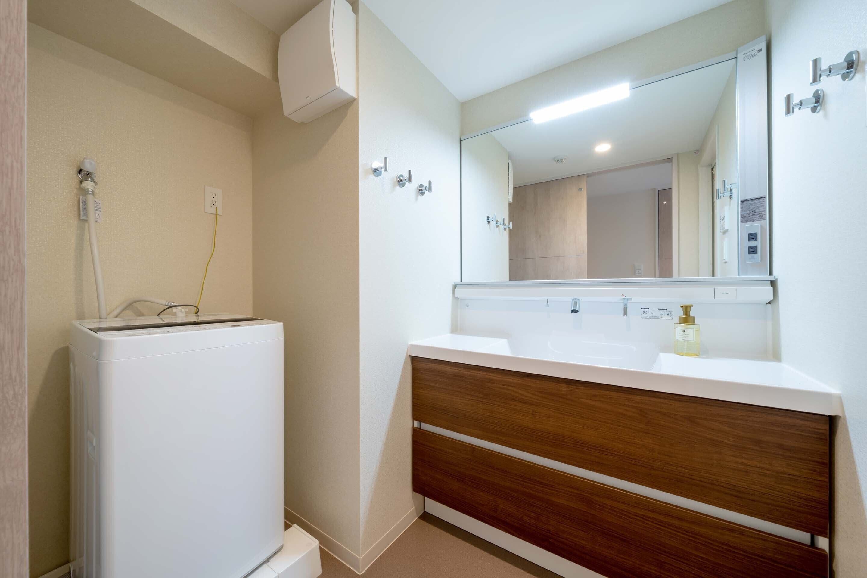 A modern bathroom with a white sink, wooden vanity, and a mirror.