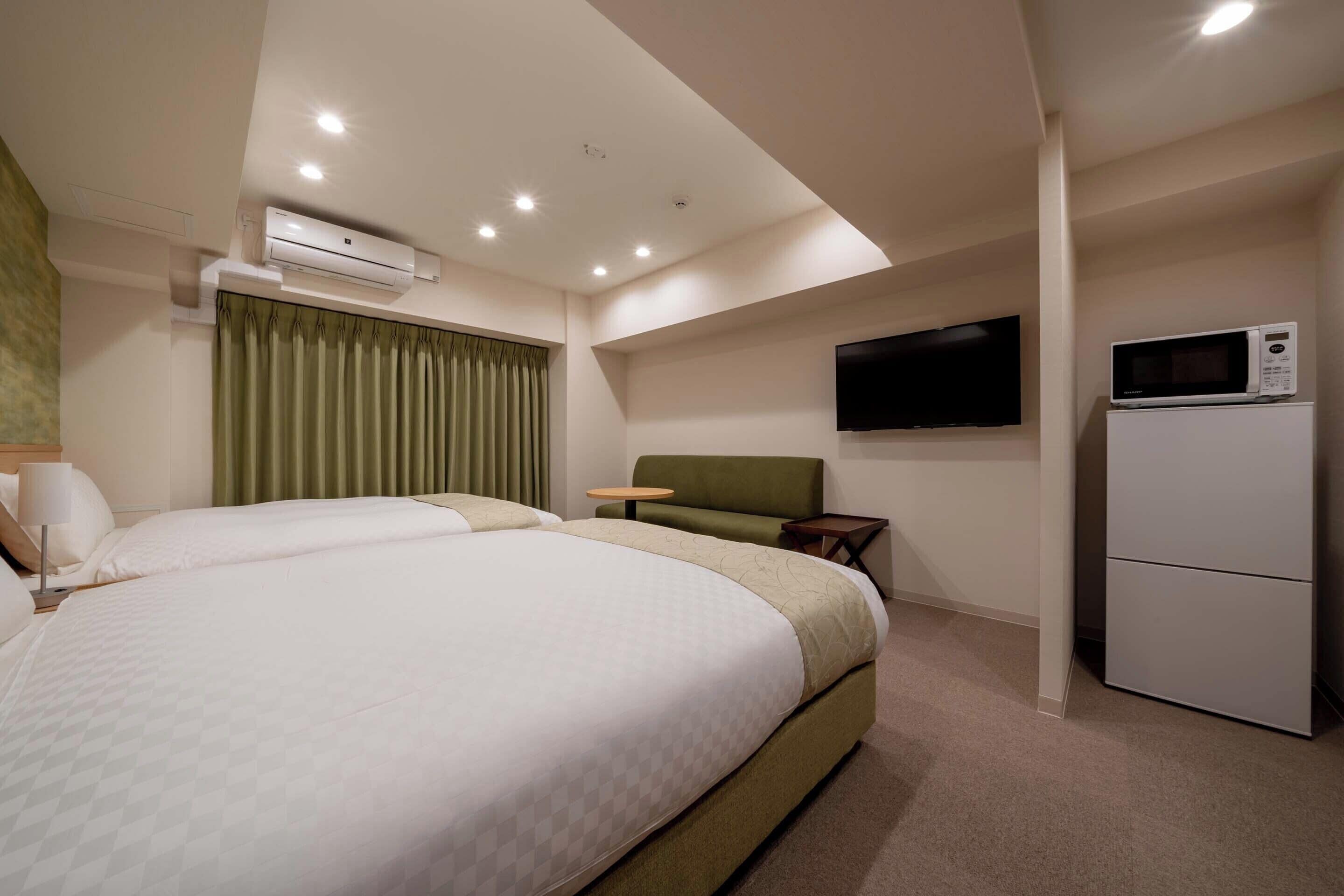 Hotelkamer met twee bedden, een flatscreen-tv, een magnetron en een airconditioning.