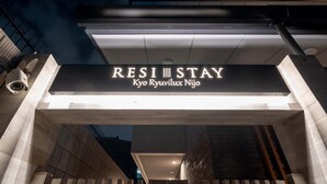 L’entrée d’un hôtel avec une enseigne indiquant : « RESI STAY Kyo Ryuvilux Nijo ».
