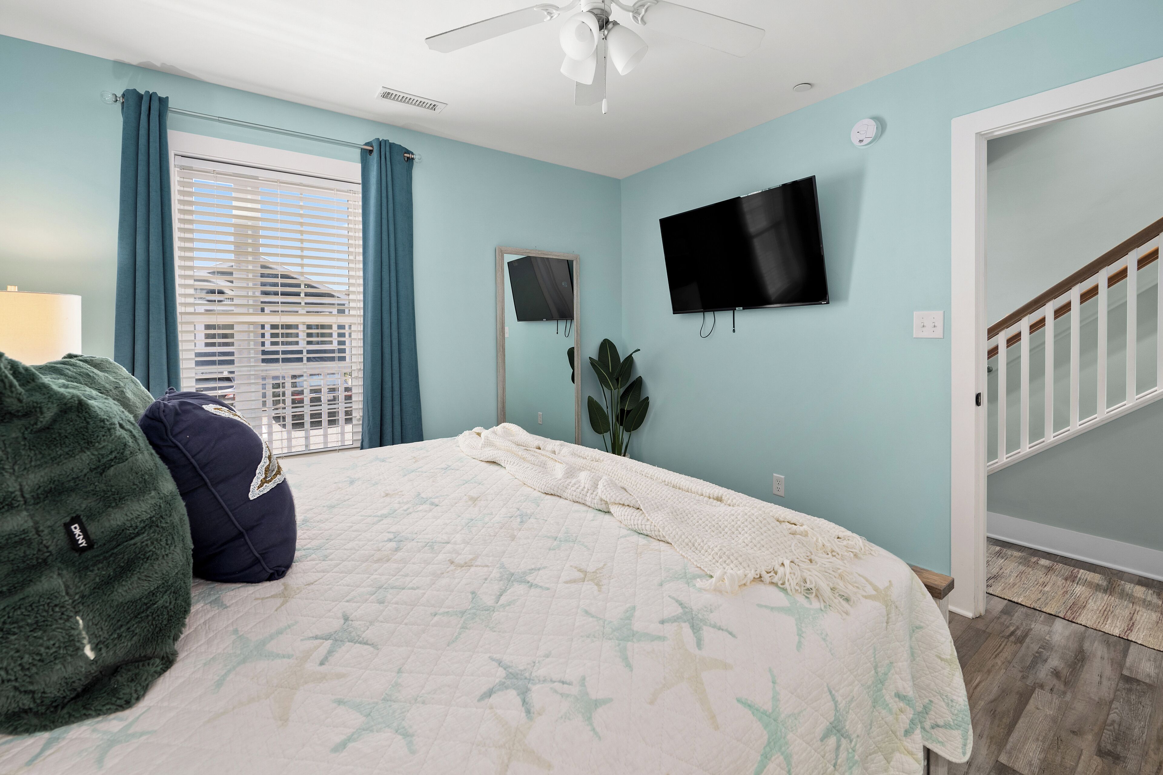 Un dormitorio con cama, televisión, ventana con cortinas y una escalera.