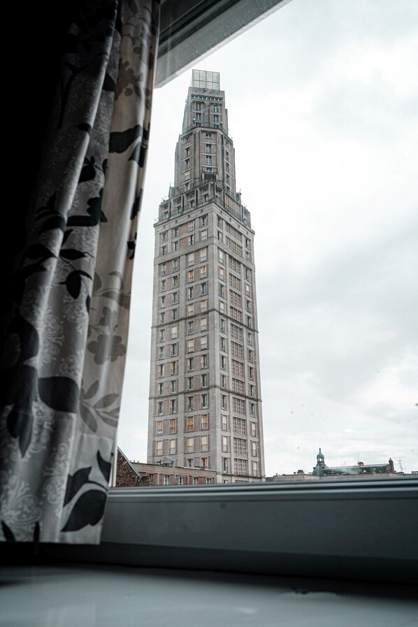 A view of a tall building through a window with floral curtains.