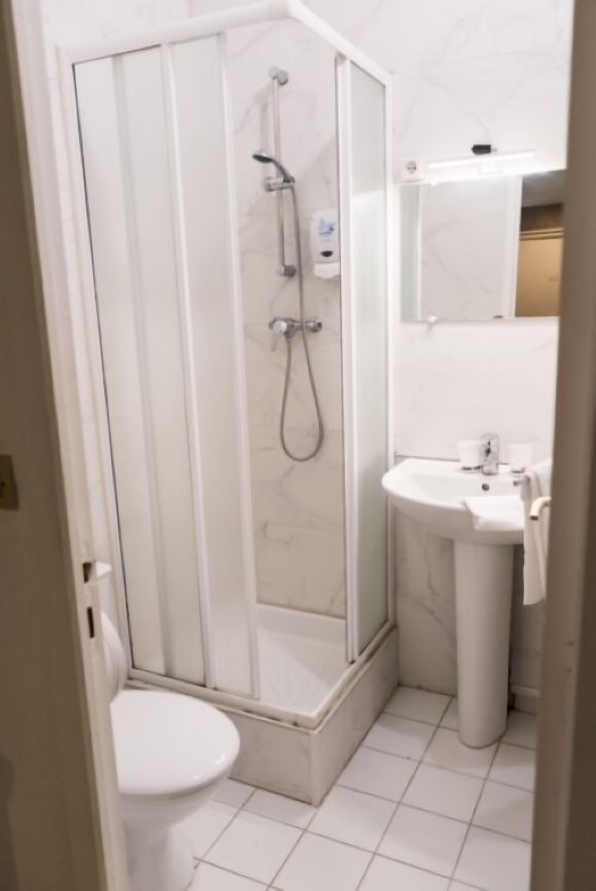 A bathroom with a glass-enclosed shower, a pedestal sink, and a toilet.