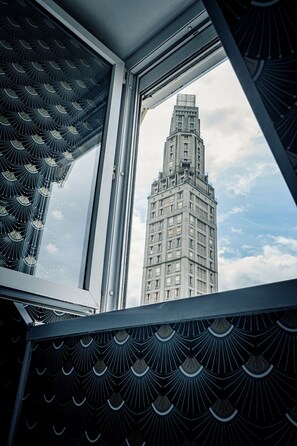 A window with a view of a tall building with a unique architectural design. - Central Anzac (Amiens)