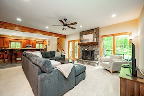 A spacious living area with a fireplace, a sofa set, and a dining area with wooden cabinets.