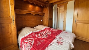 Una habitación de cabaña de madera con una cama, paredes de madera y una puerta.