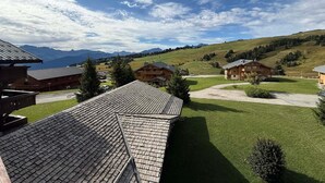 Un resort de montaña con edificios de estilo chalet, un césped bien cuidado y vistas a montañas distantes.