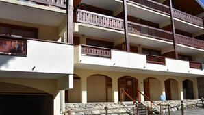 A multi-story building with balconies, a stone staircase, and a parking area. - Sunny 4-room apartment, south balcony, near cable car (Pralognan-la-Vanoise)