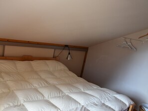 Un dormitorio con una cama grande, una lámpara colgante y un perchero.