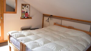 A bedroom with a wooden bed, a nightstand, a wall-mounted bulletin board, and a mirror. - Sunny 4-room apartment, south balcony, near cable car (Pralognan-la-Vanoise)