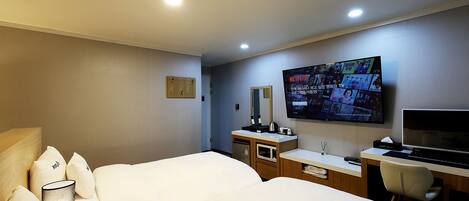 Una habitación de hotel con dos camas, un escritorio, un televisor y un minibar.