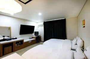 Habitación de hotel con una cama grande, un escritorio con computadora, un televisor de pantalla plana y un espejo amplio.