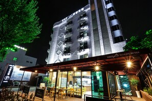 A hotel with a modern design, featuring a rooftop terrace with outdoor seating and a sign indicating it is a tourist hotel.