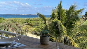 A table set for two with a view of the ocean and tropical vegetation. - Caribbean Escape - View Orient Bay and St Barth, pool and beach - 4217 (Orient Bay)