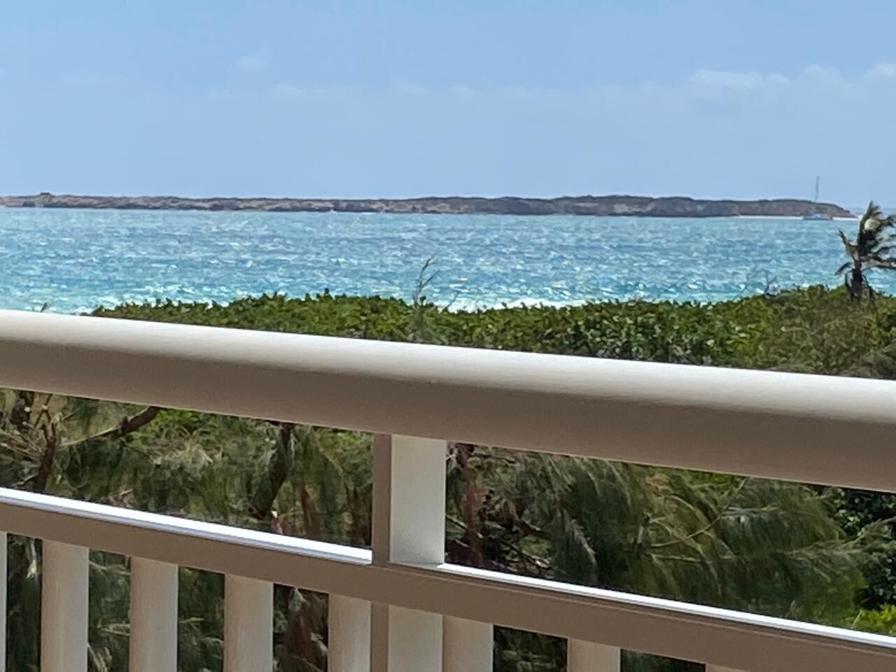 A balcony with a view of the sea and distant land.