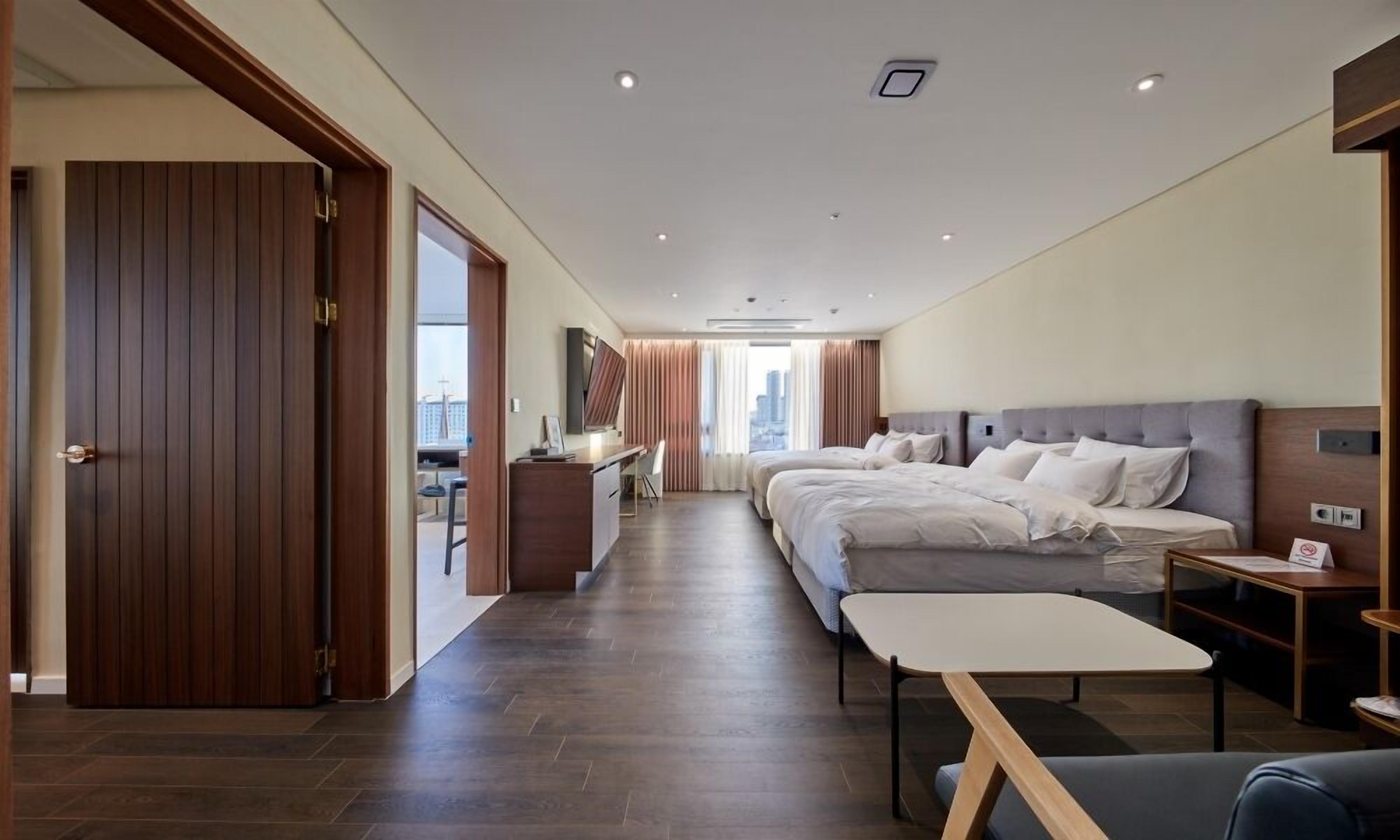 A modern hotel room with a large bed, a desk, and a view of the city.