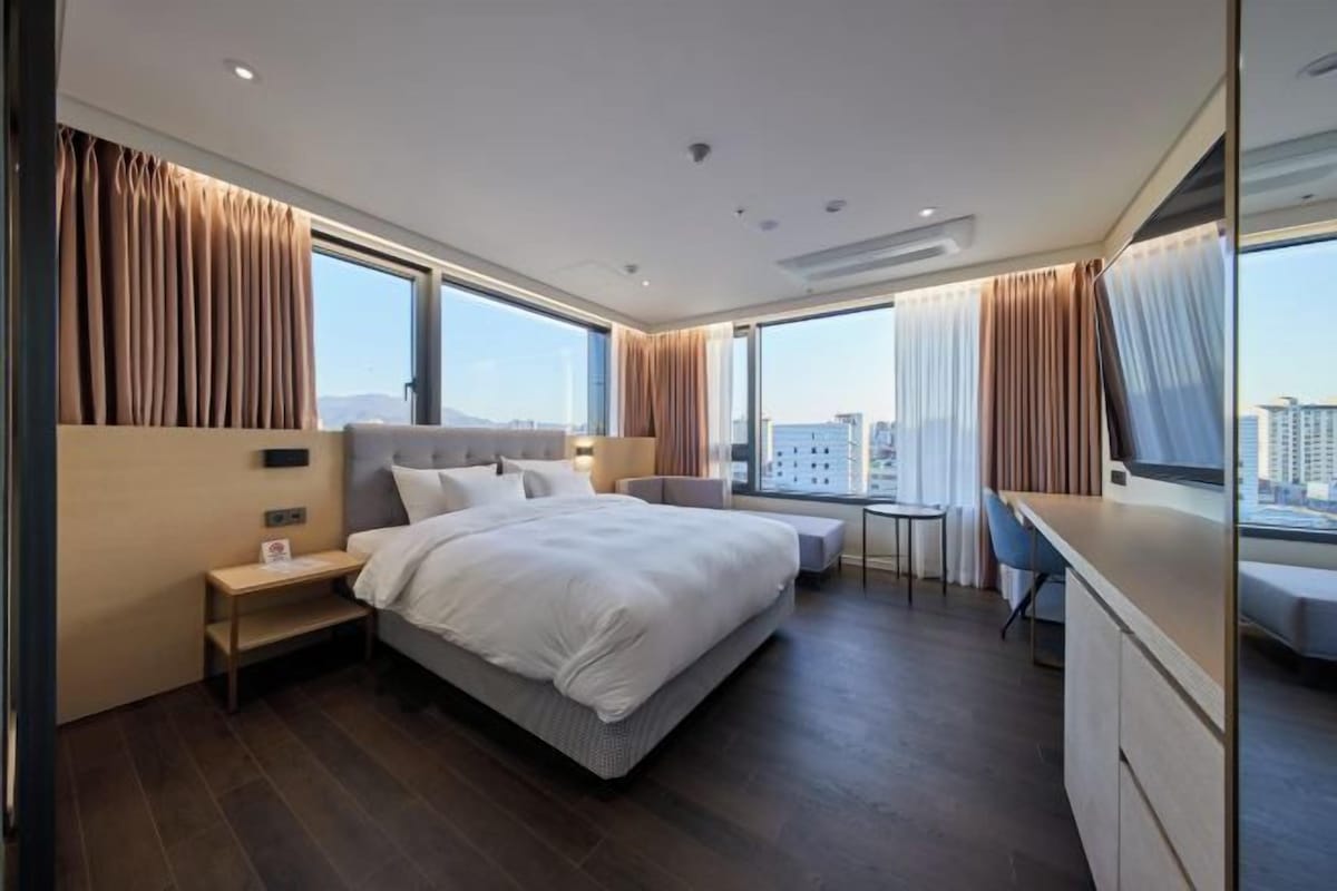 Una habitación de hotel moderna con una cama grande, un escritorio y vistas a la ciudad.