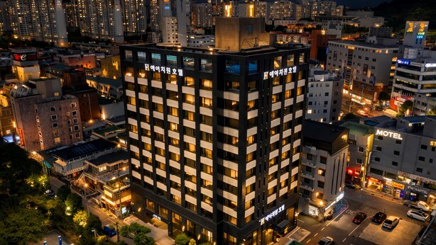 A multi-story hotel with a modern facade, multiple balconies, and a parking area in front. - Gwangju H1 Hotel (Gwangju)