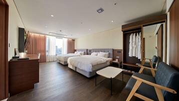 A hotel room with two beds, a desk, a chair, a wardrobe, and a large mirror.