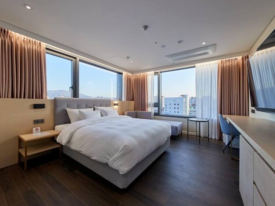 Een moderne hotelkamer met een groot bed, een bureau en uitzicht over de stad.