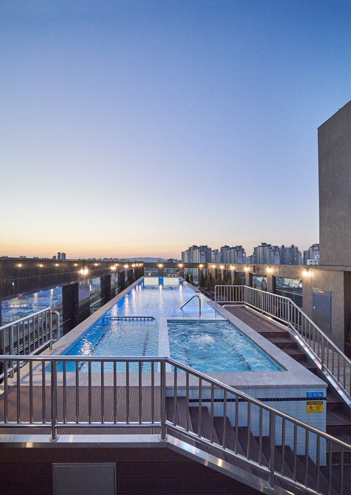 Una piscina en la azotea con vistas al perfil urbano al atardecer.