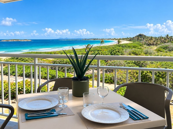 A table set for two with a view of a beach and ocean.