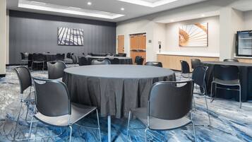 A conference room with a round table, chairs, and a carpeted floor.