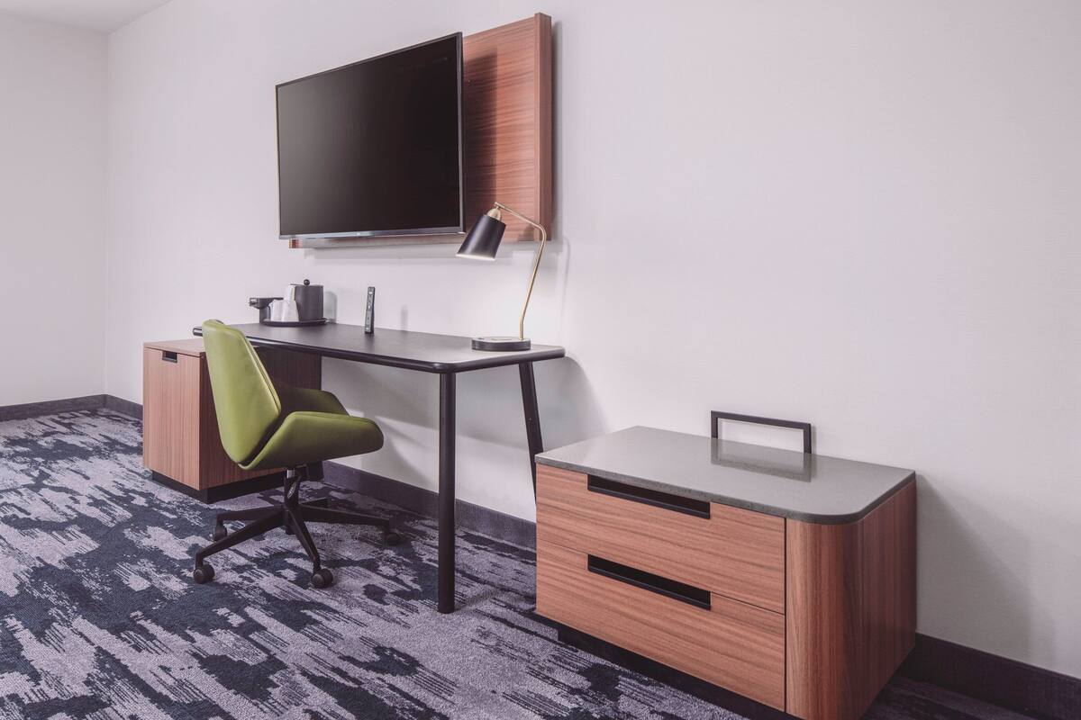 A modern office space with a desk, chair, and a mounted flat-screen TV.