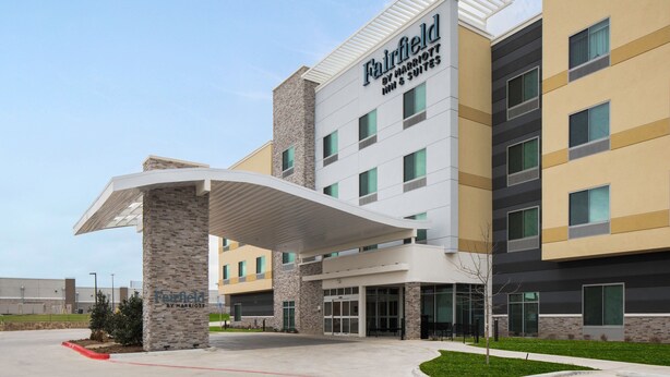 Un hotel de varios pisos con un diseño moderno, que presenta un llamativo toldo de entrada y una señal que indica que es un hotel Fairfield by Marriott.