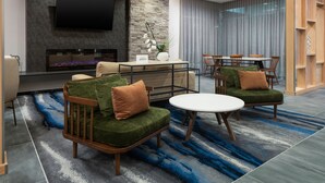 Una sala de estar moderna con chimenea, asientos cómodos, una zona de comedor y un televisor grande montado en la pared.