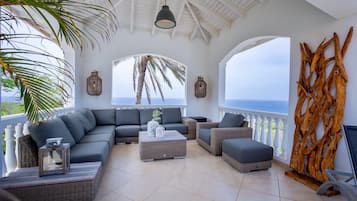 Un'ampio balcone con soffitto curvo, arredato con un divano componibile, un tavolino da caffè e un mobile TV.