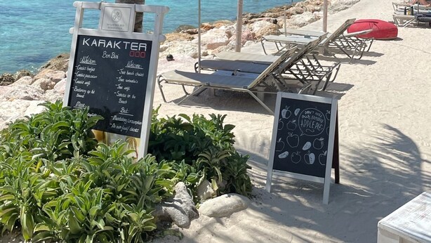 Un restaurant situé en bord de mer, avec une terrasse, un menu affiché et une vue sur l’océan.