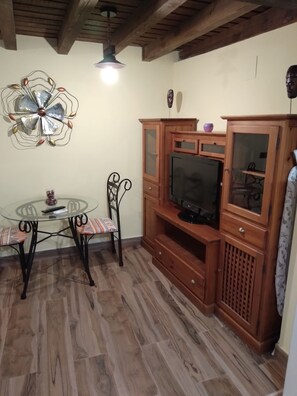 Cozy living space with a round table and two chairs, a TV, and a decorative metal wall piece.