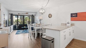 A modern kitchen with a central island, white cabinetry, and a small trash bin.