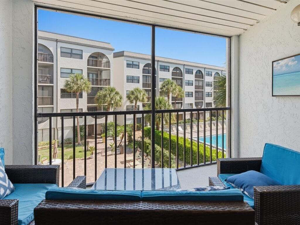 A balcony with a view of a pool and a building with multiple balconies.