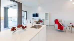 Une cuisine moderne dotée d’un grand îlot central, d’un coin repas et d’un espace de vie avec un téléviseur.