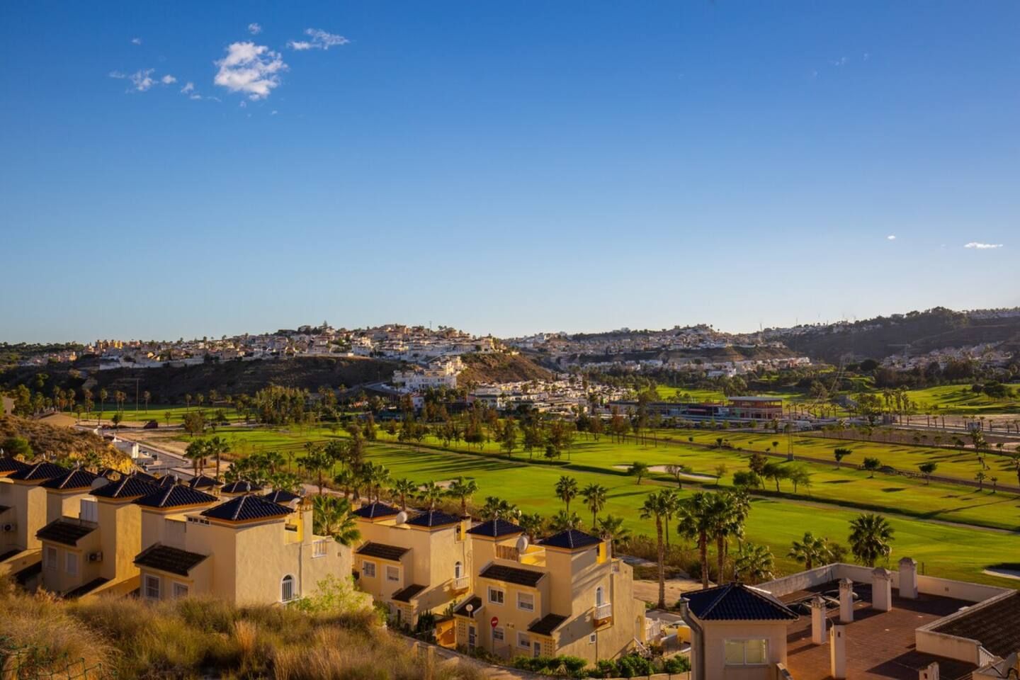 Zona residencial con casas, un campo de golf y cielo despejado.