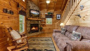 A cozy cabin interior with a stone fireplace, wooden walls, a leather couch, and a rocking chair. - Southern Serenity, Hot tub, Pool Table,  Wifi, $560 FREE tickets each paid day! (Sevierville)