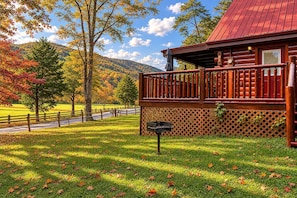 A wooden cabin with a porch, surrounded by a fenced yard and a mountain backdrop. - Southern Serenity, Hot tub, Pool Table, Wifi, $560 FREE tickets each paid day! (Sevierville)
