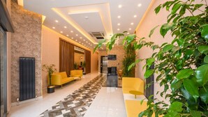 Eine moderne Lobby mit einem geometrisch gemusterten Boden, gelben Sitzgelegenheiten und Grünpflanzen.