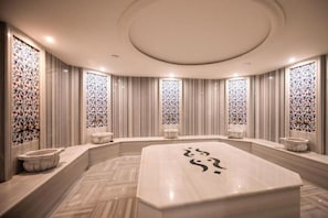 A spa room with a large central bathtub, a curved bench, and decorative glass panels on the walls. - King City Hotel Istanbul Ataturk Airport (Istanbul)
