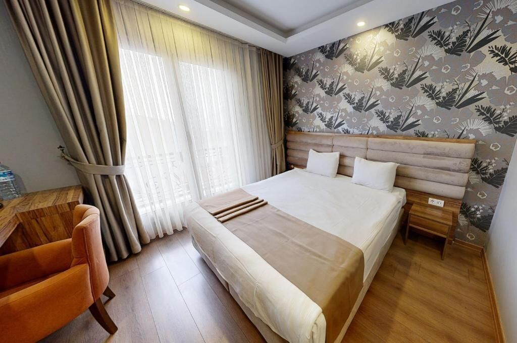 A hotel room with a large bed, wooden headboard, a desk, and a chair.